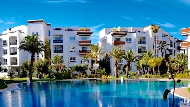 Un hôtel doté d’une piscine, de plusieurs étages et de palmiers.