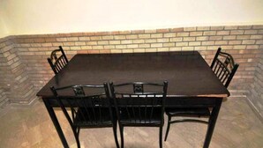 A rectangular dining table with six black chairs. The table is set against a brick wall. - Residence Babylone Marrakech 3390 (Marrakech)