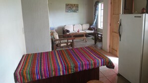 A compact living space with a sofa, a small table, and a refrigerator. - Pink house (San Antonio Palopo)