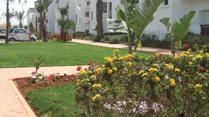 Un immeuble résidentiel doté de nombreux balcons, d’une pelouse bien entretenue et d’une variété de plantes à fleurs.