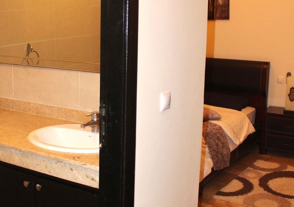 A bathroom with a sink, mirror, and a dark-colored door.