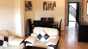 Een woonkamer met een bank, een eettafel met stoelen en kunstwerken aan de wanden.