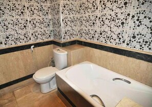 A bathroom with a toilet, bathtub, and tiled walls. - Residence Barrone Marrakech 3377 (Marrakech)