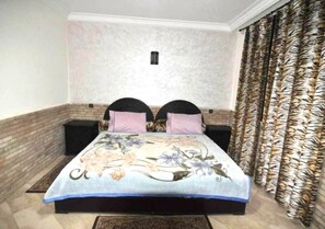 A bedroom with a bed, two nightstands, a brick accent wall, and patterned curtains. - Residence Barrone Marrakech 3377 (Marrakech)