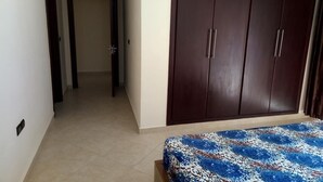 A bedroom with a bed, a wardrobe, and a hallway. - Atlantic Ocean Residence 3044 (Asilah)