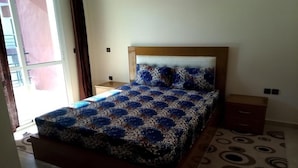 A bedroom with a bed, a nightstand, a dresser, and a patterned rug. - Atlantic Ocean Residence 3044 (Asilah)