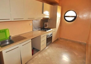 A compact kitchen with a sink, stove, and cabinets.