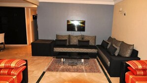 Uma sala de estar com sofá, televisão de tela plana na parede e tapete estampado.