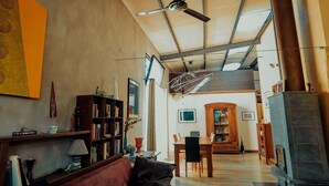 A spacious living room with a high ceiling, a fireplace, and a dining area with a wooden table and chairs. - A Casa B&B (Ravenna)