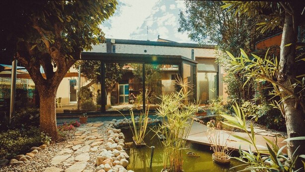 A serene garden with a pond, stone pathway, and modern architecture in the background. - A Casa B&B (Ravenna)