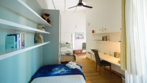 A compact room with a bed, a desk, and shelving units. - A Casa B&B (Ravenna)