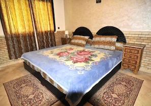 A bedroom with a bed, two nightstands, a dresser, and a patterned rug.