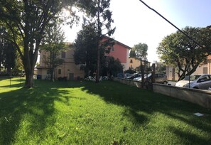 Un espacio al aire libre con césped, árboles y un edificio en el fondo.