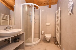 Un baño moderno con cabina de ducha de vidrio, un lavamanos blanco y un inodoro.