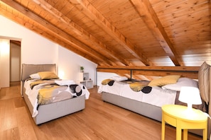 Un dormitorio acogedor en el ático con dos camas, vigas de madera y una mesita.