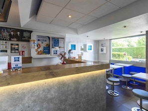 A modern interior with a reception desk, a fan, and a view of the outdoors.