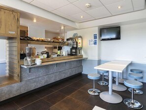 A modern cafe with a counter, coffee machines, and bar stools.