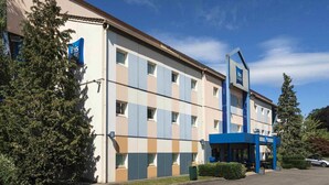 Un hôtel à la façade moderne, doté de nombreuses fenêtres et d’une entrée bleue.