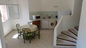 A compact kitchen with a dining area, a washing machine, and a microwave. - Mini-villa No. 4 - 2/4 people (PORTO-VECCHIO)