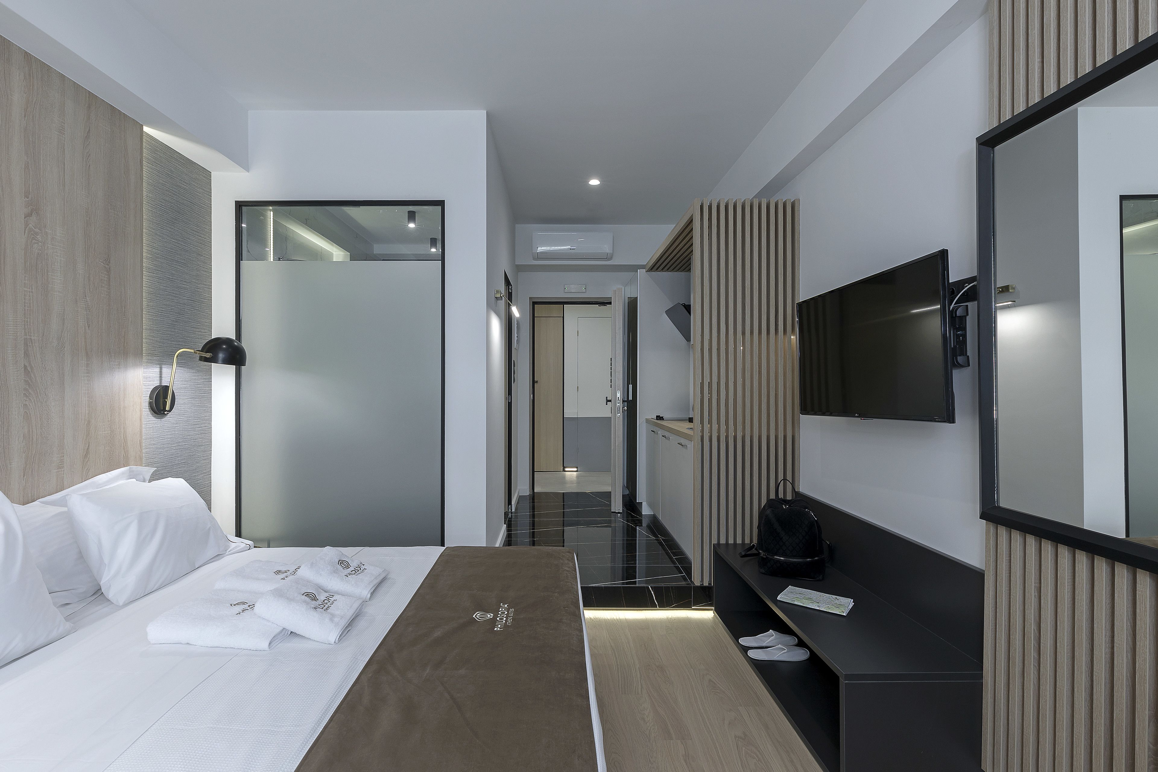 Ein modernes Hotelzimmer mit einem Bett, einem Schreibtisch, einem Flachbildfernseher und einem Spiegel.