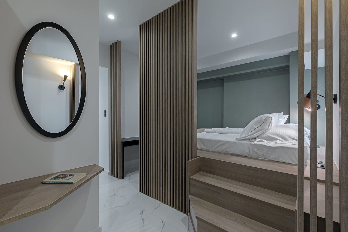 A modern bedroom with a bunk bed, a bedside table, a mirror, and a wooden partition.