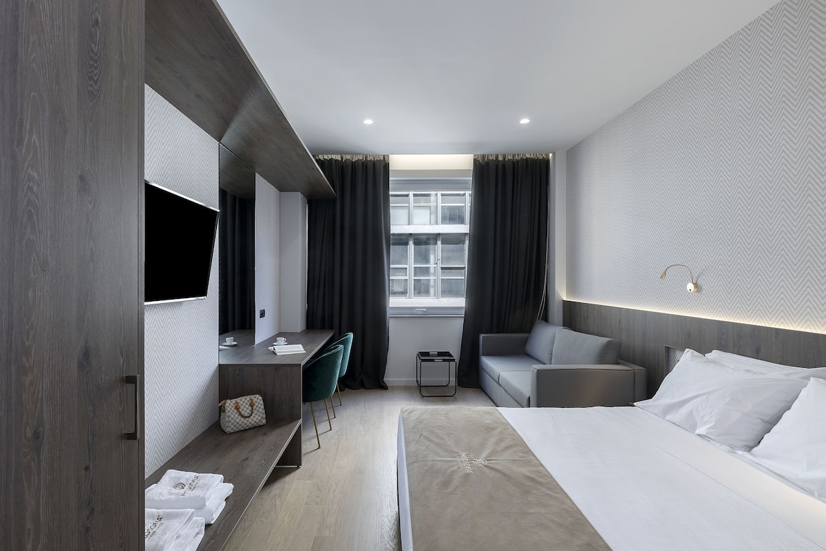 A modern hotel room with a bed, desk, and seating area.