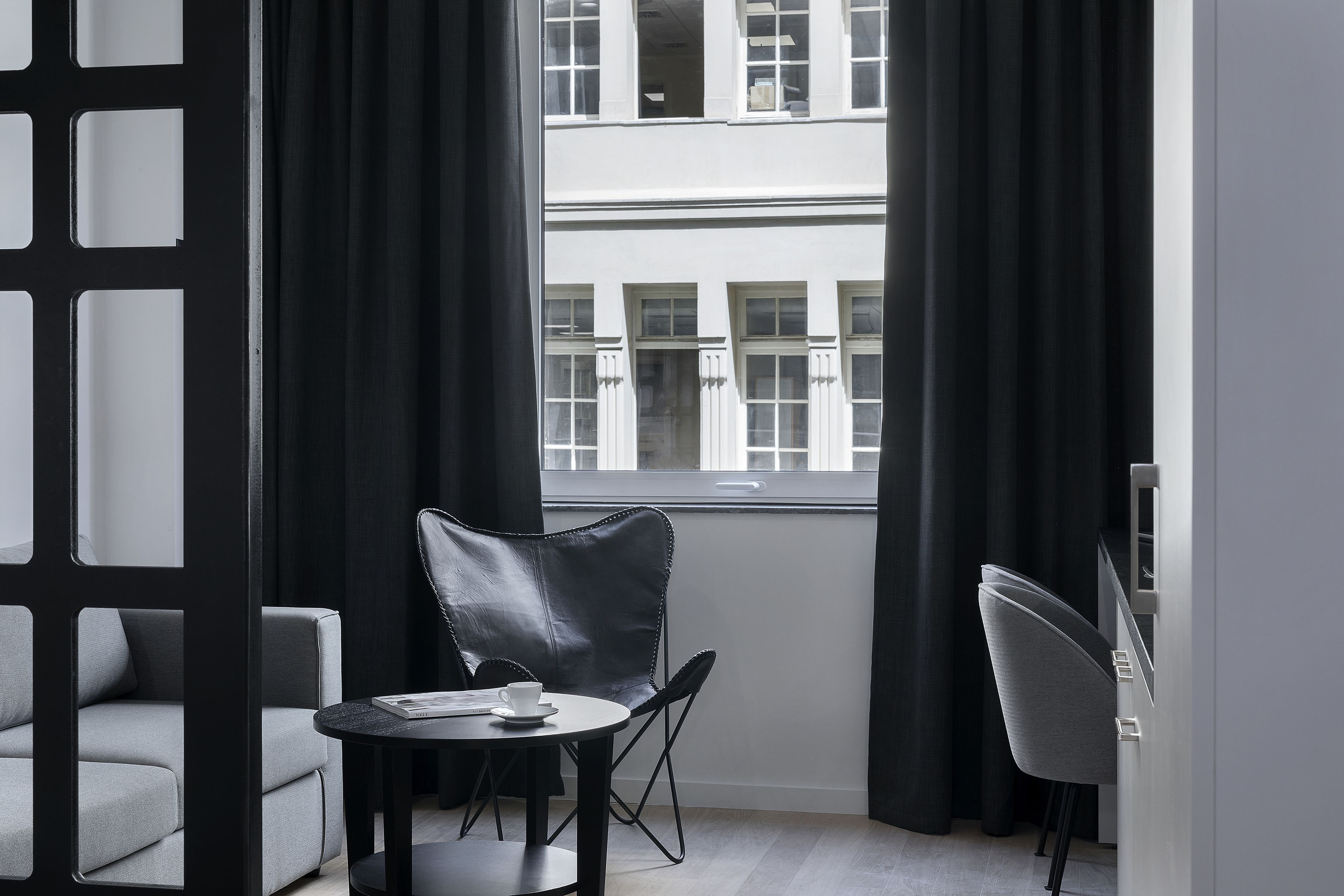 A modern room with a sofa, a chair, a small table, and a window with curtains.