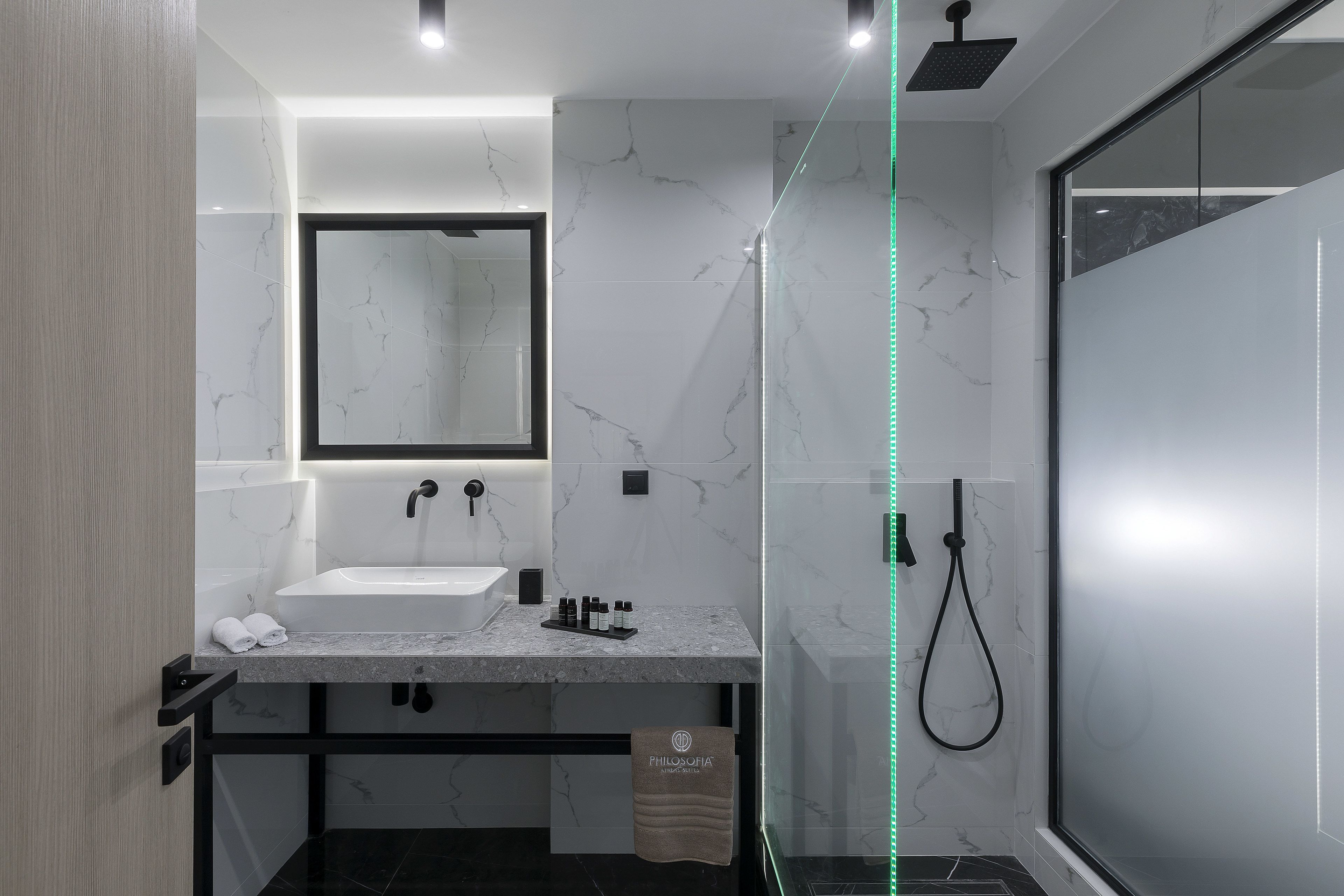 Een moderne badkamer met een marmeren wastafel, een grote spiegel en een douche met glazen wanden.
