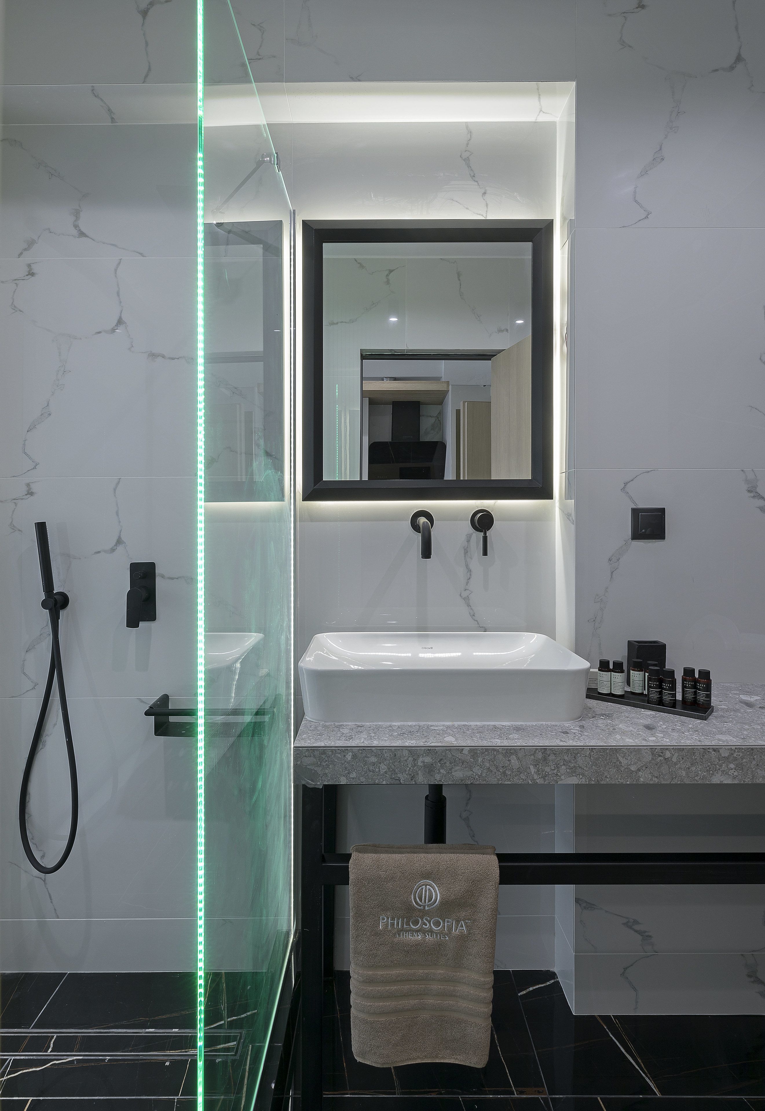 A modern bathroom with a glass-enclosed shower, a white sink, and a large mirror.