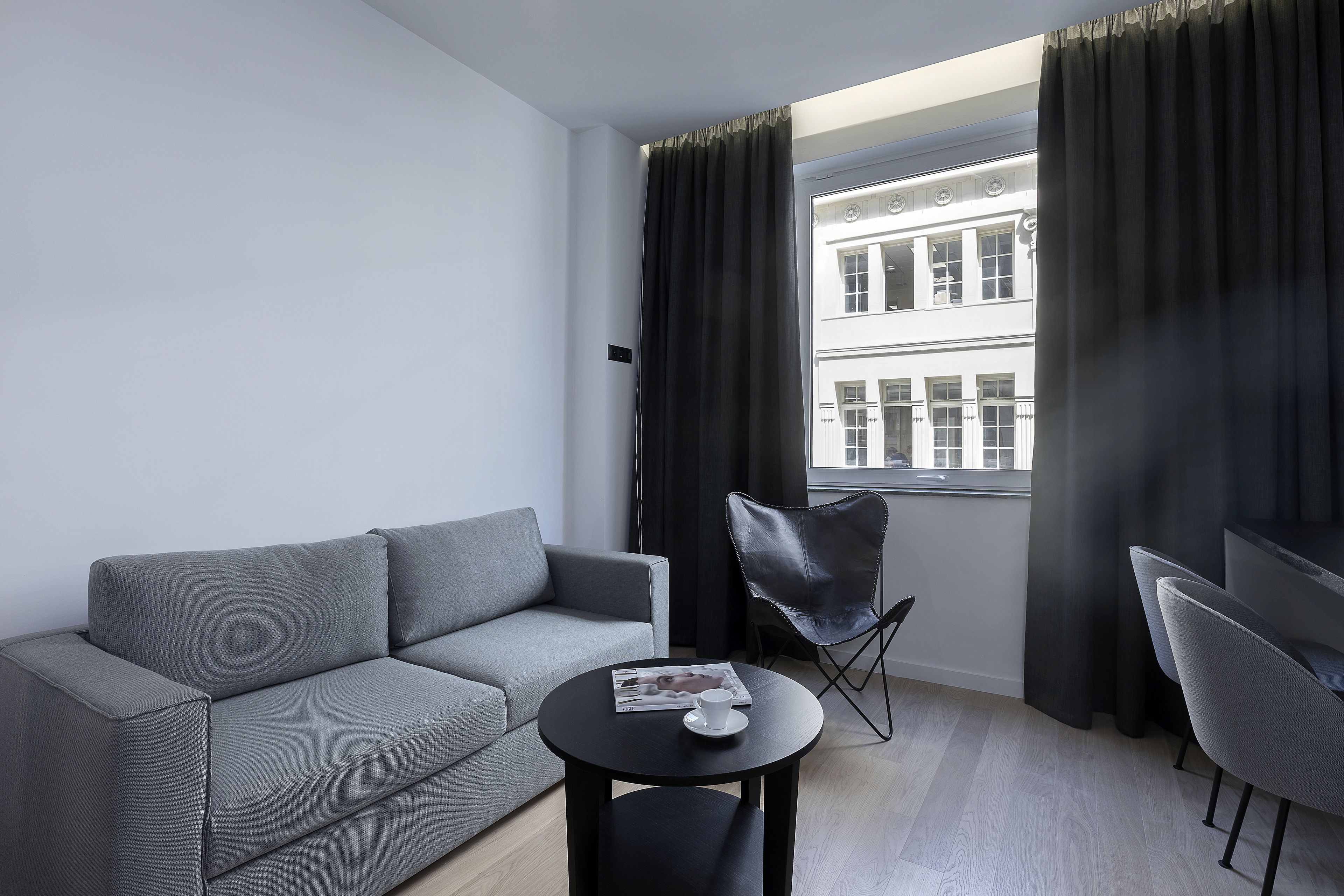 A modern living room with a grey sofa, a black coffee table, and a black leather chair.