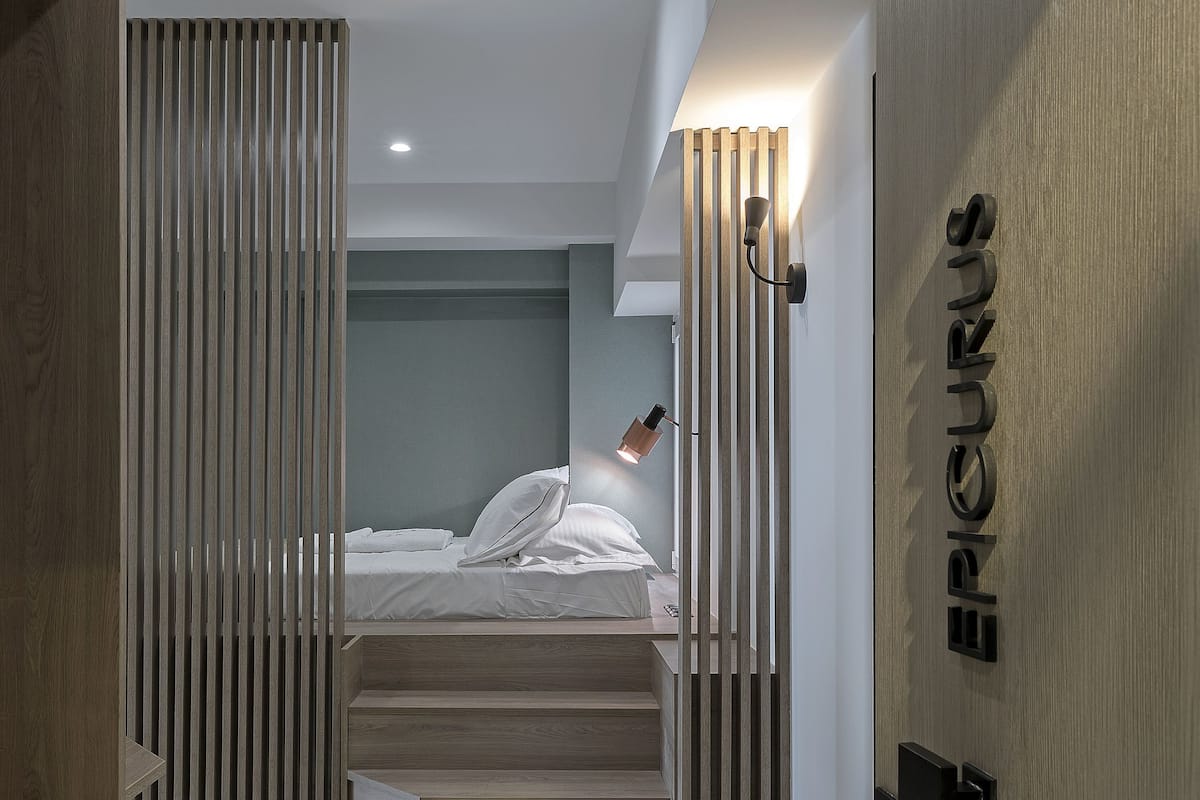 A modern bedroom with a bed, a wooden wardrobe, and a staircase leading to an upper level.