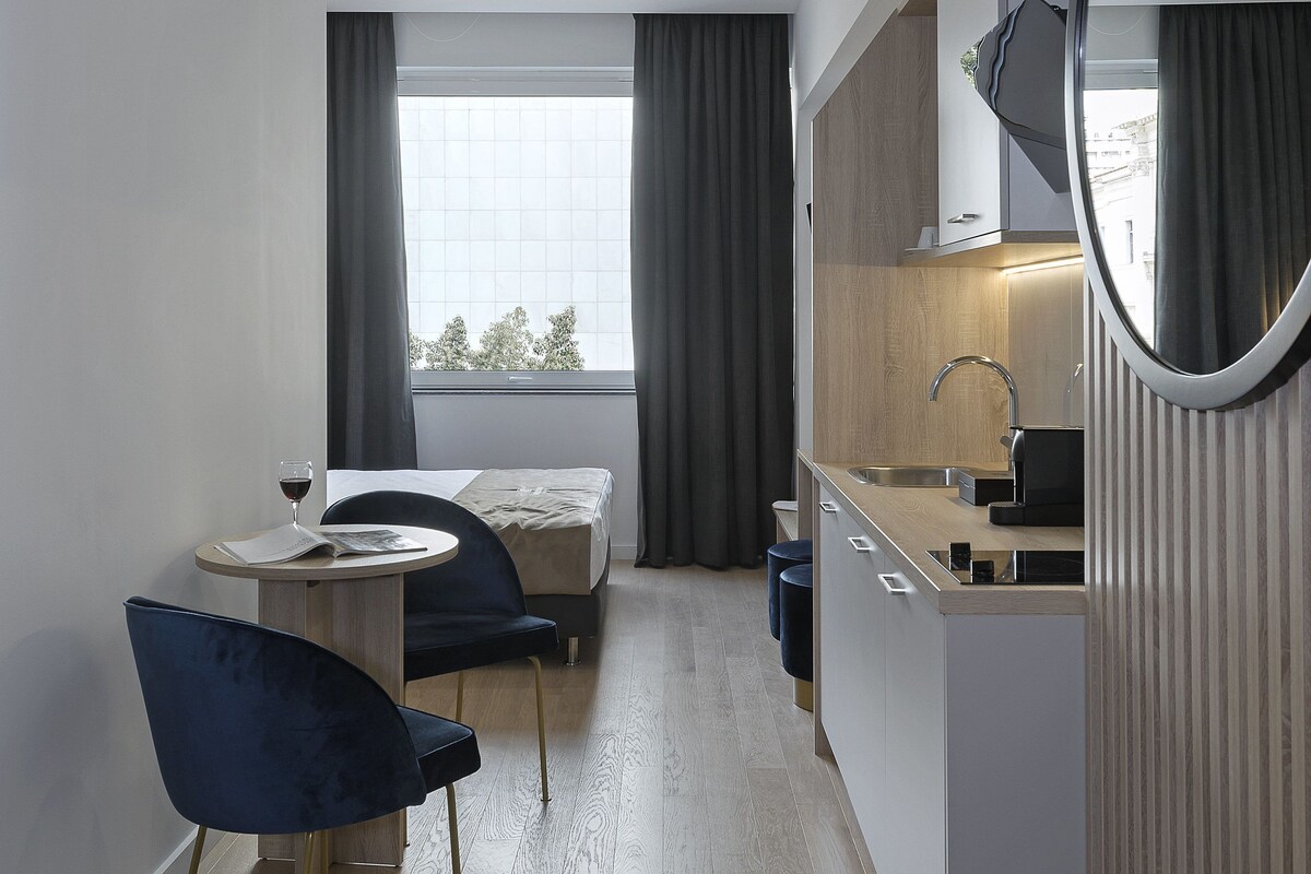 Ein modernes Hotelzimmer mit Essbereich, einem großen Spiegel und Blick aus dem Fenster.