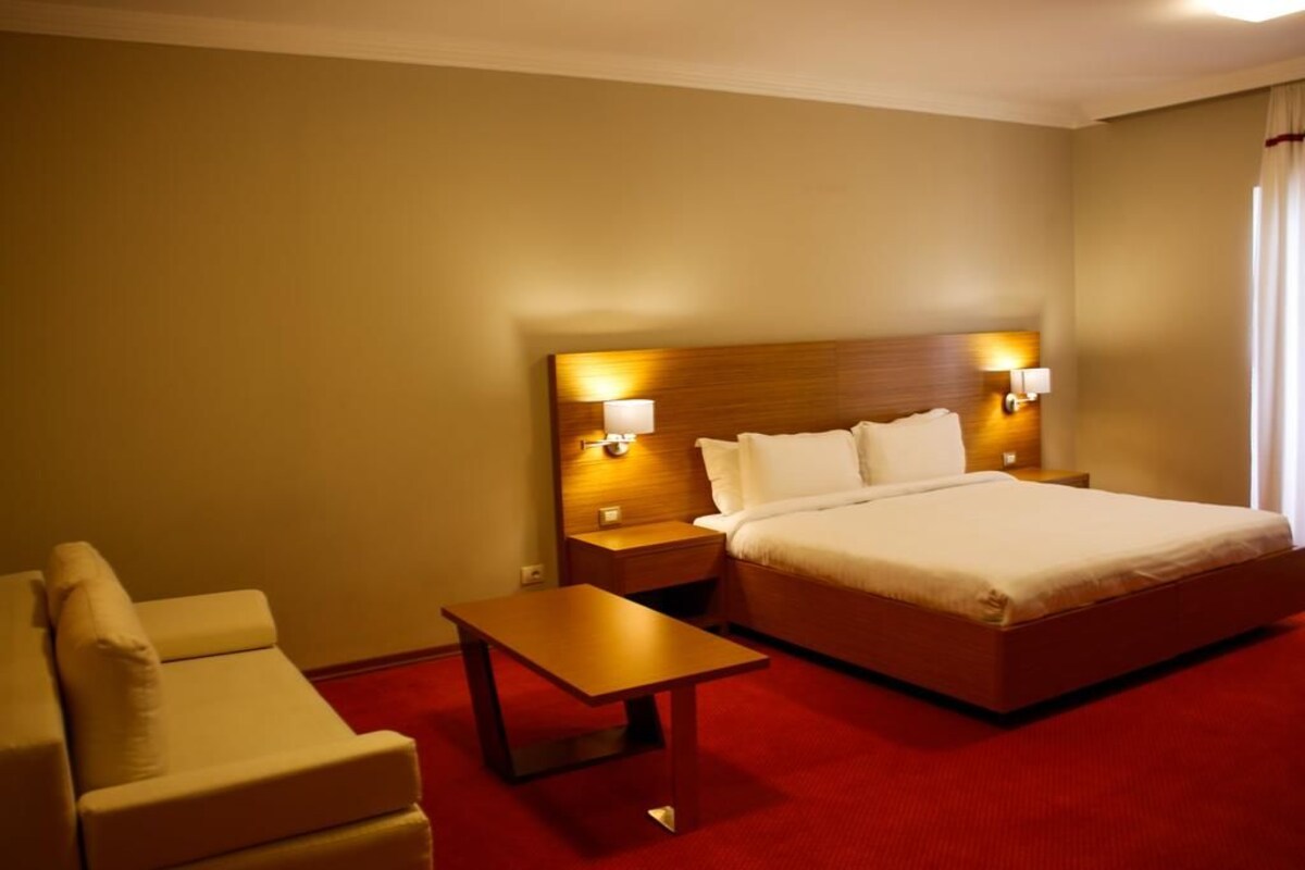 Una habitación de hotel con una cama, una mesita de noche, una mesa y una silla.