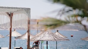 A poolside area with lounge chairs, umbrellas, and a clear view of the sea. - Hotel Jaroal (Sarandë)