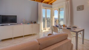 A modern living room with a sofa, a TV, a dining table with chairs, and a balcony with a view. - Fedra (Manerba del Garda)