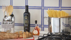 A kitchen counter with a bottle of extra virgin olive oil, a bottle of honey, a pot of spaghetti, and a basket of wooden utensils. - Casa Giovannina - charming fisherman's house with stunning views (Conca dei Marini)