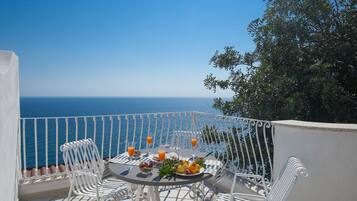Een balkon met een tafel voor twee, met uitzicht op zee.