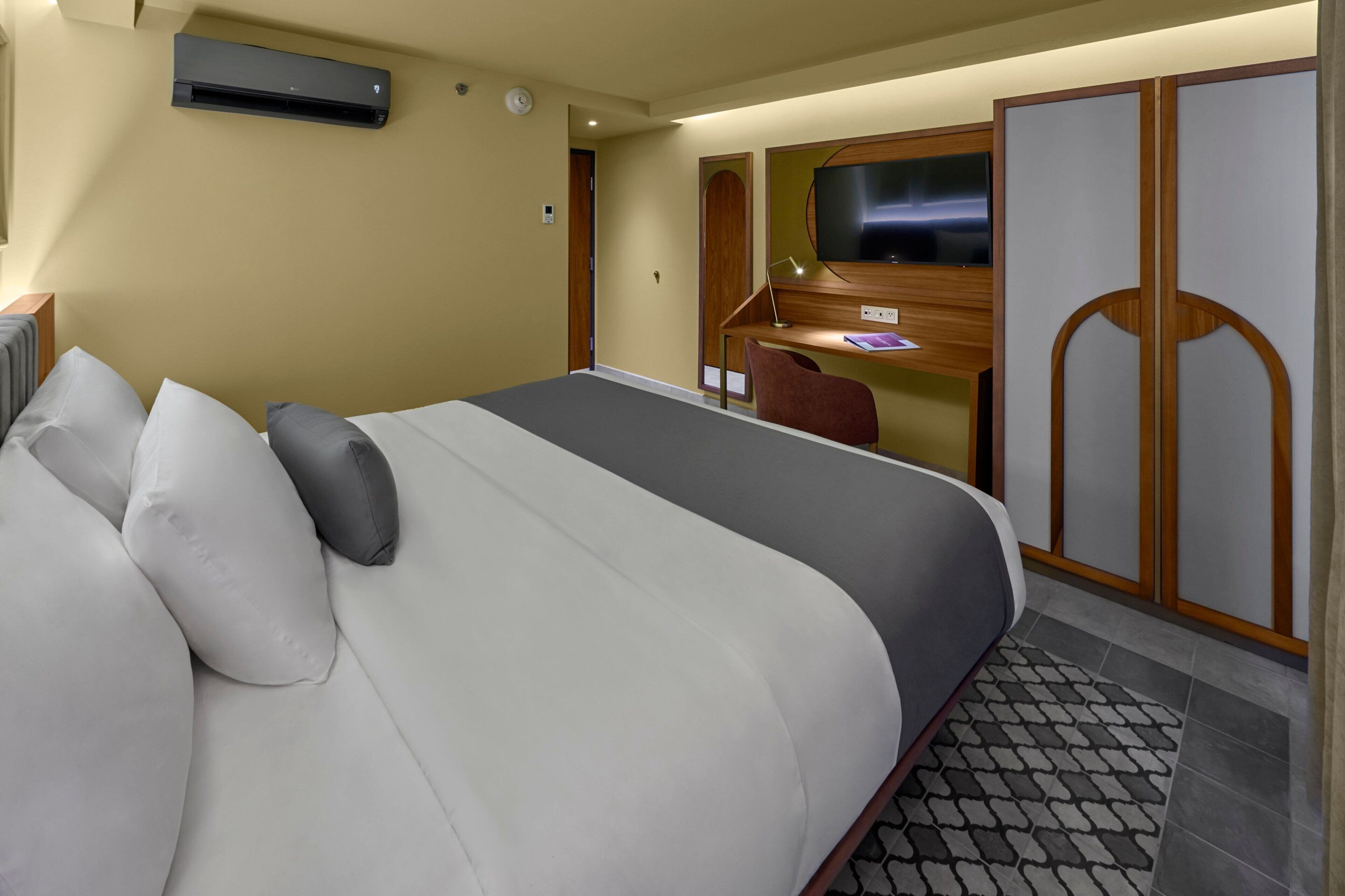 Una habitación de hotel con una cama grande, un escritorio con una silla, un televisor y un armario.