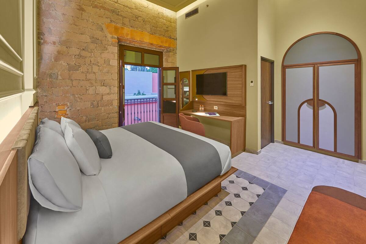 A bedroom with a bed, a desk, a TV, and a wardrobe.
