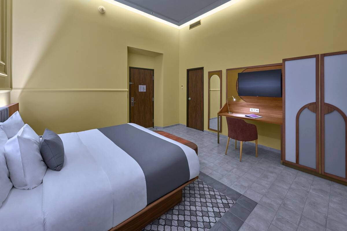 A hotel room with a bed, desk, chair, and wardrobe.