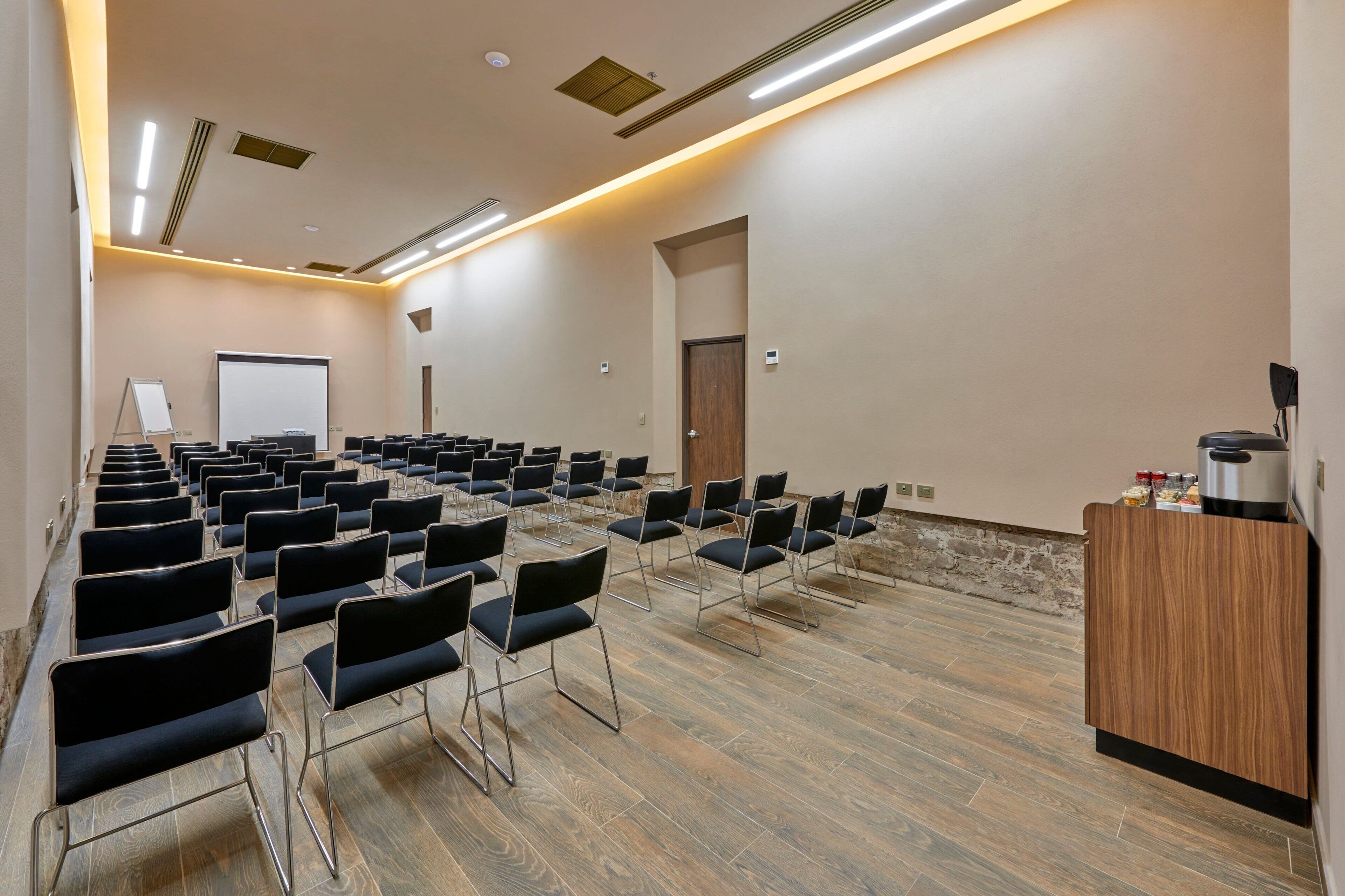 Een vergaderzaal met rijen stoelen, een whiteboard en een spreekgestoelte.