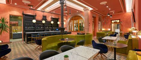 A restaurant with a bar area, green and blue seating, and a patterned floor.