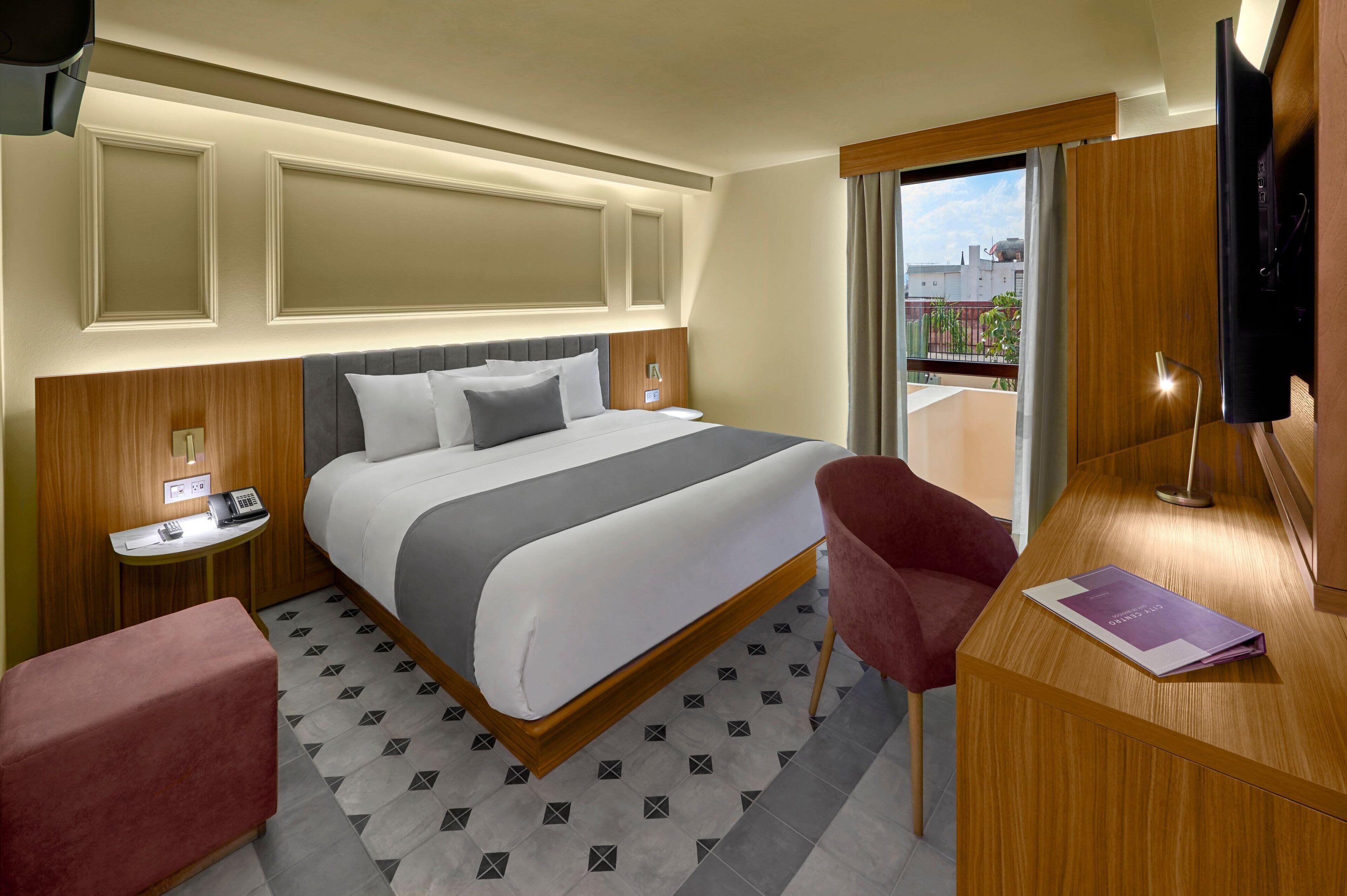 Une chambre d’hôtel comprenant un lit, des tables de chevet, un bureau, une chaise et un téléviseur.