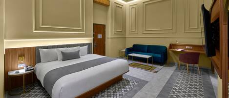 Una habitación de hotel moderna con una cama grande, un escritorio, un sofá y una televisión.