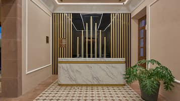 A reception area with a marble counter, a potted plant, and a patterned floor.