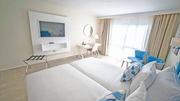 Hotelkamer met een groot bed, een bureau met stoel, een aan de muur bevestigde televisie en een raam met gordijnen.