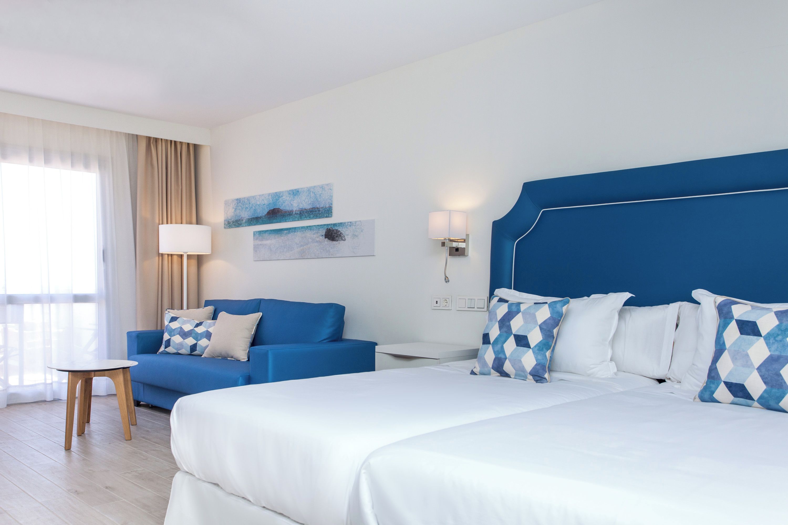 Een hotelkamer met een bed, een bank, een tafeltje en een lamp.