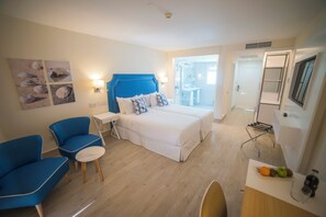 Una habitación de hotel con cama, escritorio, silla, mesita y televisor.