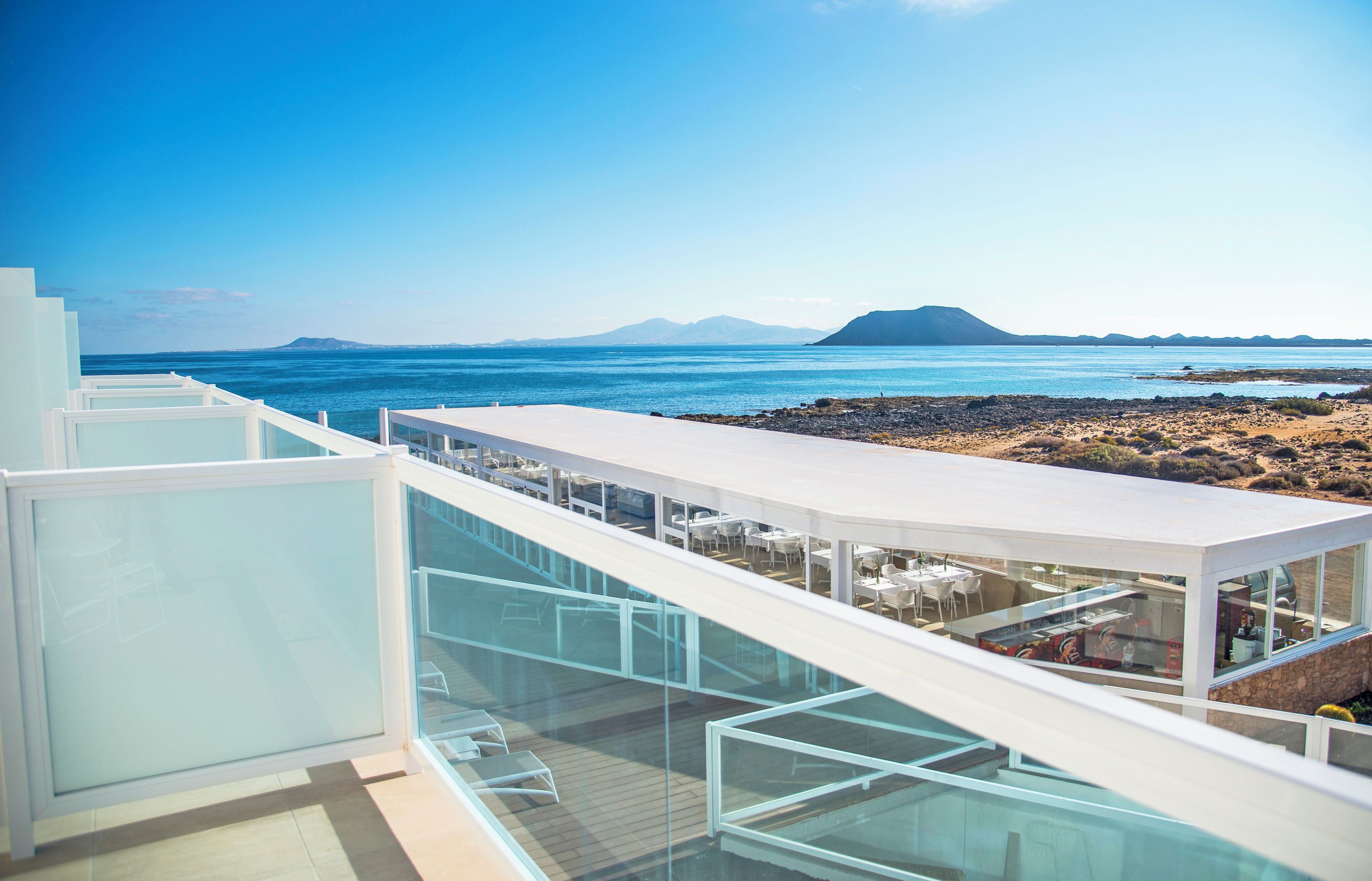 Eine moderne Dachterrasse mit Glasgeländern und Blick auf eine Küstenlandschaft.