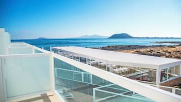 Eine moderne Dachterrasse mit Glasgeländern und Blick auf eine Küstenlandschaft.